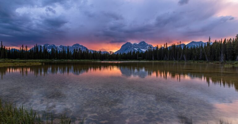 The sun sets over a pond in Spray Valley Provincal Park in Alberta, Canada.